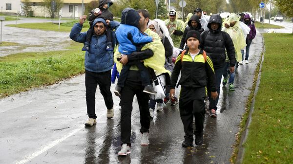 Refugees walk through the pouring rain from a public transport centre to the Lappia-building refugee reception centre in Tornio, northwestern Finland, on September 2015. - Sputnik International