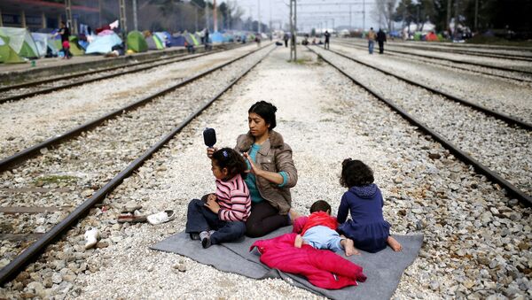 A woman sits with her children along railway tracks at a makeshift camp for migrants and refugees at the Greek-Macedonian border near the village of Idomeni, Greece, March 29, 2016. - Sputnik International