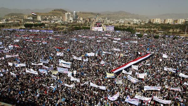 Yemenis wave national flags and hold placards during a protest against the Saudi-led coalition, commemorating one year of the alliance's military campaign against insurgents on March 26, 2016 next to the Monument to the Unknown Soldier in the Yemeni capital Sanaa - Sputnik International