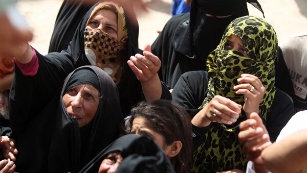 Displaced Iraqi women, who fled Ramadi, the capital of Anbar province, after it was seized by the Islamic State (IS) group, wait to get aid boxes at a makeshift camp for internally displaced persons (IDP) in Ameriyat al-Fallujah, 30 km south of Fallujah on June 6, 2015 - Sputnik International
