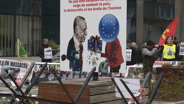 A picture taken on March 18, 2016 shows a placard depicting German Chancellor Angela Merkel (R) giving money to Turkish President Recep Tayyip Erdogan and reading not to be accomplices to crime, involves supporting peace, democracy and human rights as Kurdish people take part in a protest to call for an end of the Turkish State terror in Kurdistan, during the European Union summit in Brussels - Sputnik International
