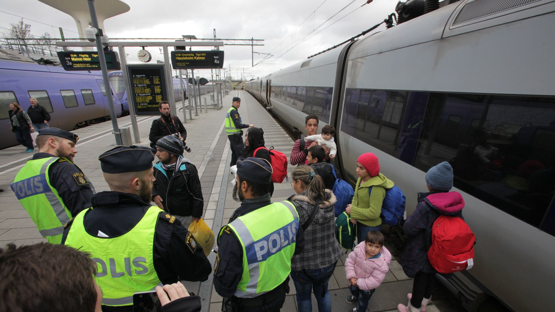 Policemen and a group of migrants stand on the platform at the Swedish end of the bridge between Sweden and Denmark in Malmo, Sweden, on November 12, 2015 - Sputnik International, 1920, 11.02.2022