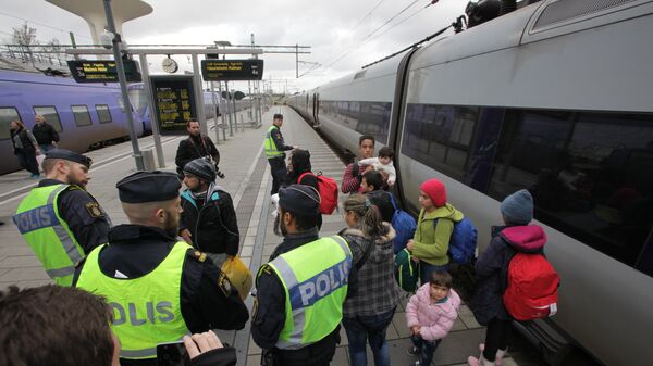 Policemen and a group of migrants stand on the platform at the Swedish end of the bridge between Sweden and Denmark in Malmo, Sweden, on November 12, 2015 - Sputnik International