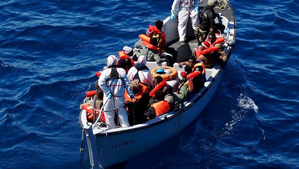Migrants sit on a rescue boat during a rescue operation of migrants by Italian Navy vessels in this March 18, 2016 handout picture. - Sputnik International