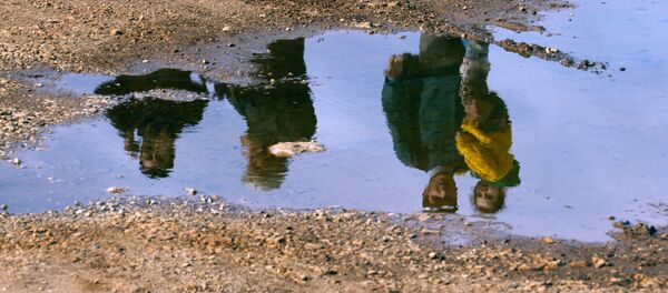 Syrian refugees are reflected in a puddle as they wait on a roadside after Turkish police prevented them from sailing off to the Greek island of Farmakonisi by dinghies, near a beach in the western Turkish coastal town of Didim, Turkey March 9, 2016. Syrian refugees are reflected in a puddle as they wait on a roadside after Turkish police prevented them from sailing off to the Greek island of Farmakonisi by dinghies, near a beach in the western Turkish coastal town of Didim, Turkey March 9, 2016. - Sputnik International