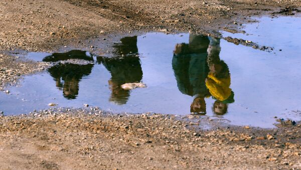 Syrian refugees are reflected in a puddle as they wait on a roadside after Turkish police prevented them from sailing off to the Greek island of Farmakonisi by dinghies, near a beach in the western Turkish coastal town of Didim, Turkey March 9, 2016. - Sputnik International