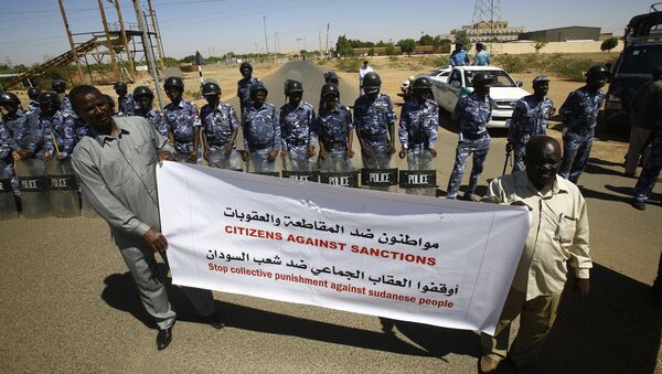 Sudanese police stand guard as two men hold a banner outside the US embassy in the capital Khartoum on November 3, 2015, to protest against sanctions imposed on their country by the United States - Sputnik International