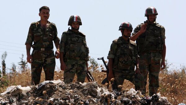 Syrian soldiers stand guard near a mass grave (File) - Sputnik International