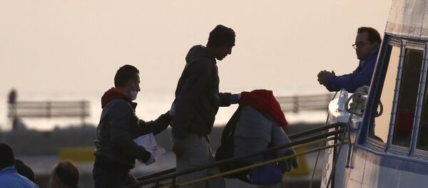 A Frontex officer (L) escorts a migrant as he boards on a Turkish-flagged passenger boat to be returned to Turkey, on the Greek island of Lesbos, April 4, 2016. - Sputnik International