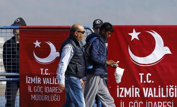 A migrant is escorted by a Turkish police officer as he arrives in the Turkish coastal town of Dikili, Turkey, April 4, 2016 - Sputnik International