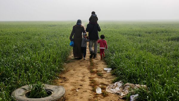 A family walks through a field at a makeshift camp for migrants and refugees at the Greek-Macedonian border near the village of Idomeni, Greece, April 4, 2016. - Sputnik International