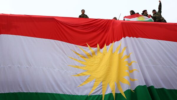 Iraqi Kurdish youths wave a national flag as they stand above a giant flag of Kurdistan during celebrations of Flag Day on December 17, 2015 - Sputnik International