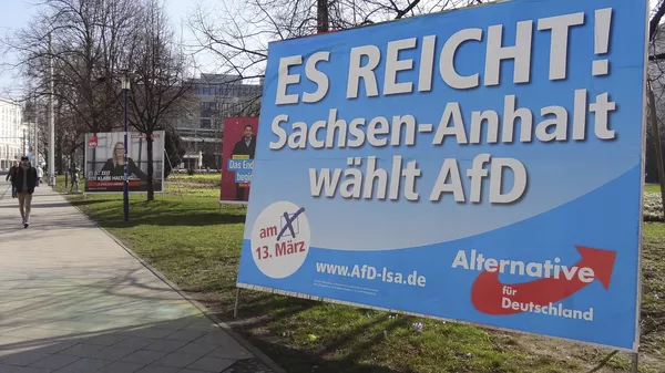 A man walks past a campaign poster of right-populist AfD party reading It's enough - Saxony-Anhalt elects AfD in Magdeburg, Germany. - Sputnik International