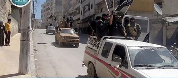 This image posted on the Twitter page of Syria's al-Qaida-linked Nusra Front on Saturday April 25, 2015, which is consistent with AP reporting, shows Nusra Front fighters standing on their vehicles and waving their group's flags as they tour the streets of Jisr al-Shughour, Idlib province, Syria - Sputnik International