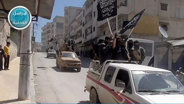 This image posted on the Twitter page of Syria's al-Qaida-linked Nusra Front on Saturday April 25, 2015, which is consistent with AP reporting, shows Nusra Front fighters standing on their vehicles and waving their group's flags as they tour the streets of Jisr al-Shughour, Idlib province, Syria - Sputnik International