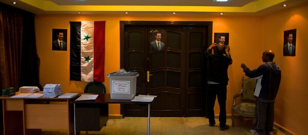 An empty ballot box with Arabic that reads, Syrian Arab Republic, Damascus Governorate, Election ballot box, number 210, is seen at a polling station as workers hang portraits of Syrian President Bashar Assad in Damascus, Syria, Tuesday, April 12, 2016. - Sputnik International
