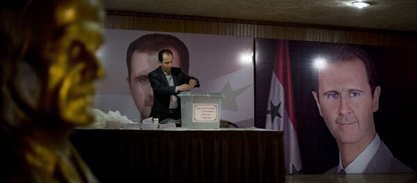A Syrian election official waits for voters at a polling station with posters of President Bashar Assad during the parliamentary election in Damascus, Syria A Syrian election official waits for voters at a polling station with posters of President Bashar Assad during the parliamentary election in Damascus, Syria - Sputnik International