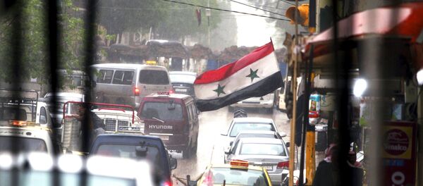 Vehicles travel on a busy road near a Syrian national flag in Qamishli, Syria April 11, 2016. - Sputnik International