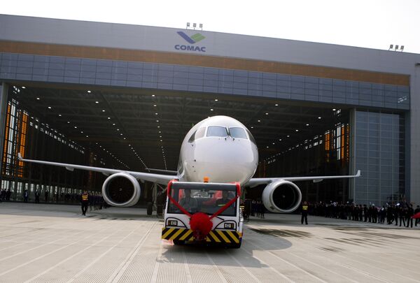 Chinese workers wave flags as a truck pulls out the first twin-engine 158-seater C919 passenger plane made by The Commercial Aircraft Corp. of China (COMAC) during a ceremony at the company's hangar near the Pudong International Airport in Shanghai, China. (File) Chinese workers wave flags as a truck pulls out the first twin-engine 158-seater C919 passenger plane made by The Commercial Aircraft Corp. of China (COMAC) during a ceremony at the company's hangar near the Pudong International Airport in Shanghai, China. (File) - Sputnik International
