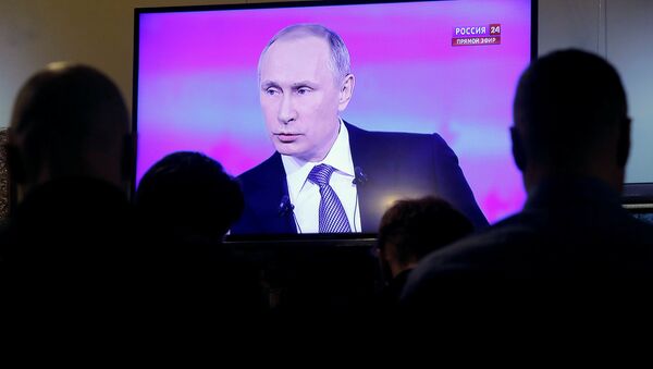 Journalists watch a live broadcast on an electronic screen showing nationwide call-in attended by Russian President Vladimir Putin in Moscow, Russia, April 14, 2016 - Sputnik International