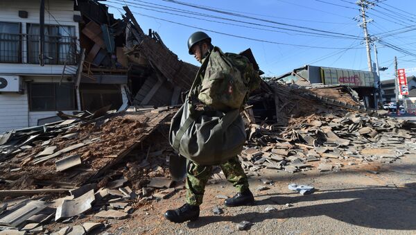 A member of the self defense forces walks past a collapsed house in Mashiki, Kumamoto prefecture on April 16, 2016 - Sputnik International