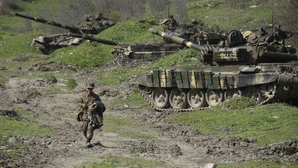 A soldier of the defense army of Nagorny Karabakh walks past tanks at a field position outside the village of Mataghis, some 70km north of Karabakh's capital Stepanakert, on April 6, 2016 - Sputnik International