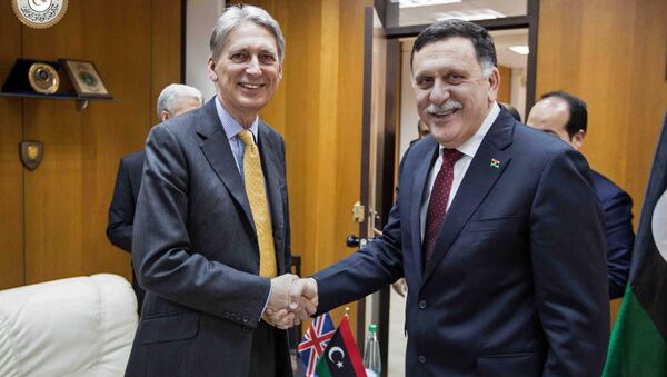 In this photo provided by the Libyan Government of National Accord, Libyan prime minister-designate Fayez Serraj , right and British Foreign Secretary Philip Hammond shake hands for photographers in Tripoli, Libya, Monday, April 18, 2016. - Sputnik International