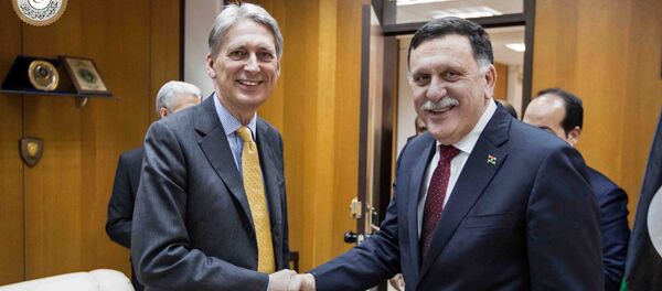 In this photo provided by the Libyan Government of National Accord, Libyan prime minister-designate Fayez Serraj , right and British Foreign Secretary Philip Hammond shake hands for photographers in Tripoli, Libya, Monday, April 18, 2016. In this photo provided by the Libyan Government of National Accord, Libyan prime minister-designate Fayez Serraj , right and British Foreign Secretary Philip Hammond shake hands for photographers in Tripoli, Libya, Monday, April 18, 2016. - Sputnik International