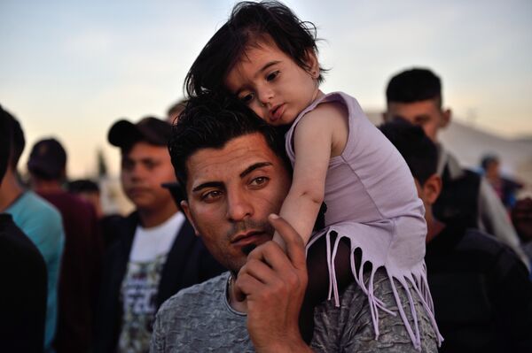 A man carries a child on his shoulders at the migrant and refugee makeshift camp near the village of Idomeni on the Greek-Macedonian border on April 16, 2016. - Sputnik International