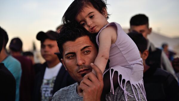 A man carries a child on his shoulders at the migrant and refugee makeshift camp near the village of Idomeni on the Greek-Macedonian border on April 16, 2016. - Sputnik International