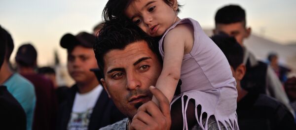A man carries a child on his shoulders at the migrant and refugee makeshift camp near the village of Idomeni on the Greek-Macedonian border on April 16, 2016. - Sputnik International