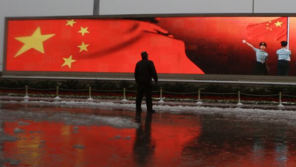 Chinese man stands near a screen displaying the Chinese national flag (File) - Sputnik International