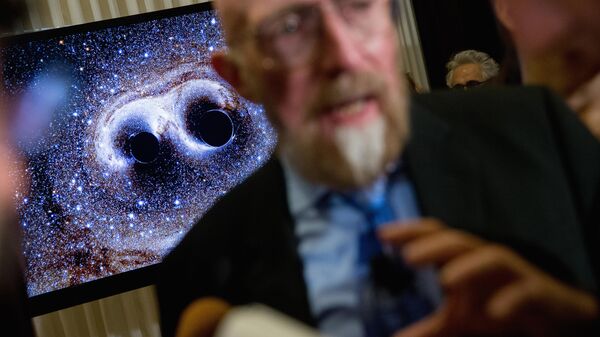visual of gravitational waves from two converging black holes is depicted on a monitor behind Laser Interferometer Gravitational-Wave Observatory (LIGO) Co-Founder Kip Thorne as he speaks to members of the media following a news conference at the National Press Club in Washington, Thursday, Feb. 11, 2016 - Sputnik International