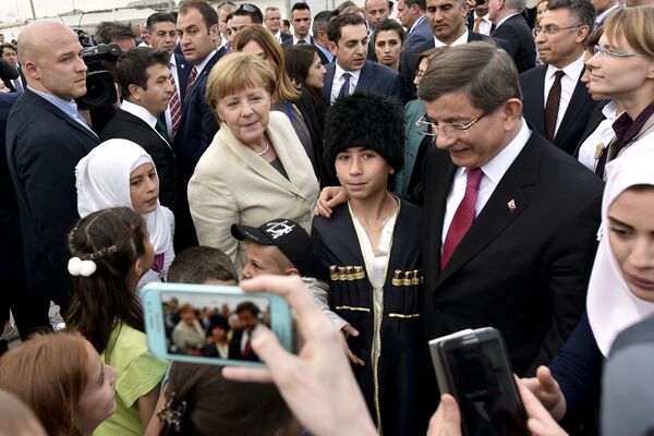 Turkish Prime Minister Ahmet Davutoglu and German Chancellor Angela Merkel pose for a picture with refugees in Nizip refugee camp near Gaziantep, Turkey, April 23, 2016 Turkish Prime Minister Ahmet Davutoglu and German Chancellor Angela Merkel pose for a picture with refugees in Nizip refugee camp near Gaziantep, Turkey, April 23, 2016 - Sputnik International