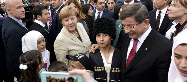 Turkish Prime Minister Ahmet Davutoglu and German Chancellor Angela Merkel pose for a picture with refugees in Nizip refugee camp near Gaziantep, Turkey, April 23, 2016 Turkish Prime Minister Ahmet Davutoglu and German Chancellor Angela Merkel pose for a picture with refugees in Nizip refugee camp near Gaziantep, Turkey, April 23, 2016 - Sputnik International
