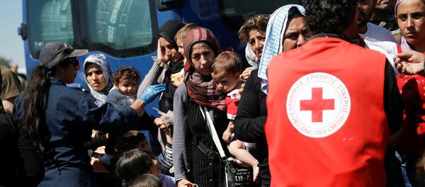 A woman holds two children as refugees and migrants wait to board a bus that will transfer them from a makeshift camp at the port of Piraeus to a newly built relocation centre in the port town of Skaramagkas, in western Athens, Greece April 18, 2016 - Sputnik International