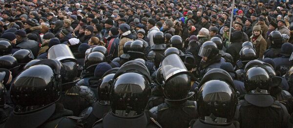 Riot police officers stand in line in front of protesters, some wanting closer links to Russia, others demanding a crackdown on corruption, outside the parliament in Chisinau, Moldova, Thursday, Jan. 21, 2016 - Sputnik International