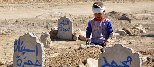 Ali Hamza, 8, sits at the graves of his brother, Mohammed, and sister Asinat, who were killed at their school when a suicide car bomb attack near Qabak elementary school in the Shiite Turkomen village of Qabak, just outside the town of in Tal Afar (File) - Sputnik International