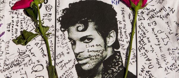 Flowers lay on a T-shirt signed by fans of singer Prince at a makeshift memorial place created outside Apollo Theater in New York. - Sputnik International