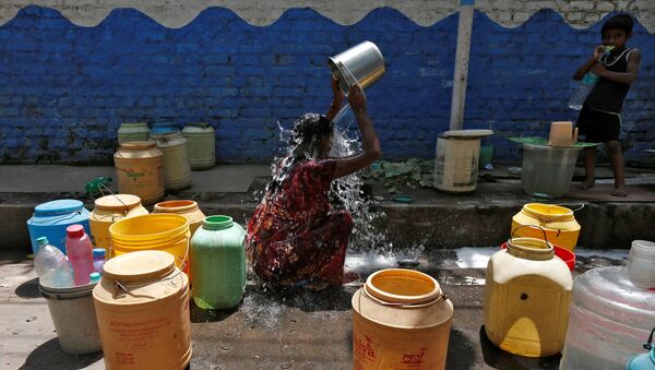 A woman bathes at a roadside municipal tap in a slum area on a hot summer day, India, April 22, 2016. - Sputnik International