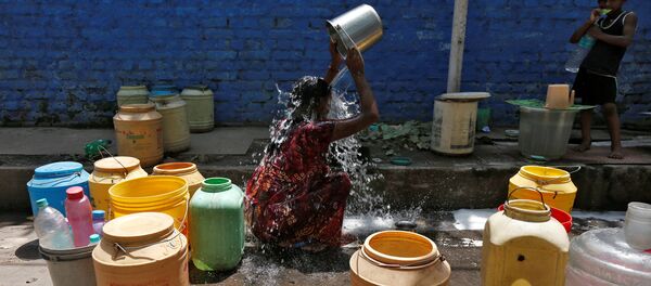 A woman bathes at a roadside municipal tap in a slum area on a hot summer day, India, April 22, 2016. - Sputnik International