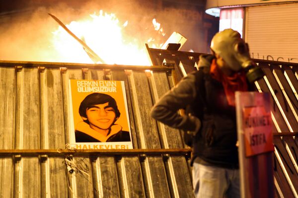 A protester stands in front of a barricade bearing a portrait of Berkin Elvan, the 15-year-old boy who died from injuries suffered during last year's anti-government protests, following clashes between police and demonstrators after the funeral of Elvan, in Istanbul on March 12, 2014. A protester stands in front of a barricade bearing a portrait of Berkin Elvan, the 15-year-old boy who died from injuries suffered during last year's anti-government protests, following clashes between police and demonstrators after the funeral of Elvan, in Istanbul on March 12, 2014. - Sputnik International