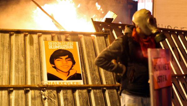 A protester stands in front of a barricade bearing a portrait of Berkin Elvan, the 15-year-old boy who died from injuries suffered during last year's anti-government protests, following clashes between police and demonstrators after the funeral of Elvan, in Istanbul on March 12, 2014. - Sputnik International
