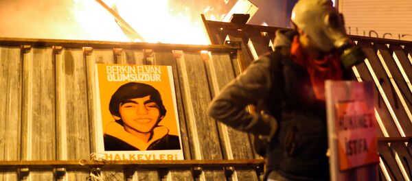 A protester stands in front of a barricade bearing a portrait of Berkin Elvan, the 15-year-old boy who died from injuries suffered during last year's anti-government protests, following clashes between police and demonstrators after the funeral of Elvan, in Istanbul on March 12, 2014. A protester stands in front of a barricade bearing a portrait of Berkin Elvan, the 15-year-old boy who died from injuries suffered during last year's anti-government protests, following clashes between police and demonstrators after the funeral of Elvan, in Istanbul on March 12, 2014. - Sputnik International