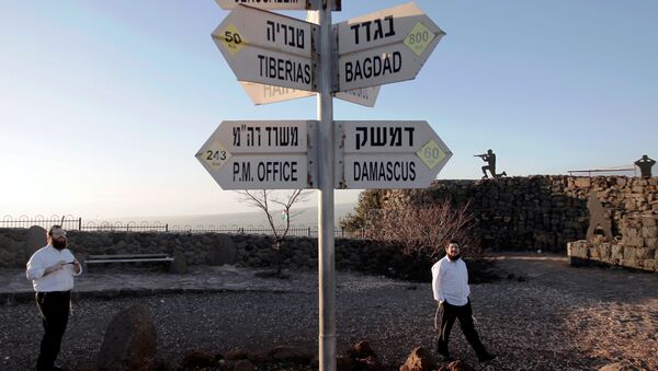 Israelis walk near a sign for tourists showing the distance to Damascus and Baghdad among other destinations at an army post on Mount Bental in the Israeli-annexed Golan Heights on March 10, 2016. - Sputnik International