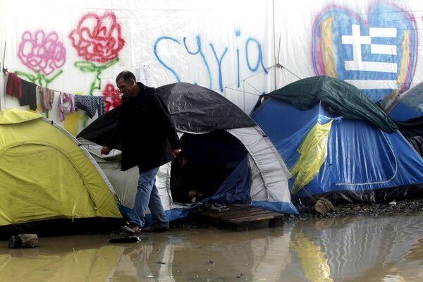 A refugee walks next to tents following heavy rainfall at a makeshift camp for migrants and refugees at the Greek-Macedonian border near the village of Idomeni, Greece, April 24, 2016. A refugee walks next to tents following heavy rainfall at a makeshift camp for migrants and refugees at the Greek-Macedonian border near the village of Idomeni, Greece, April 24, 2016. - Sputnik International