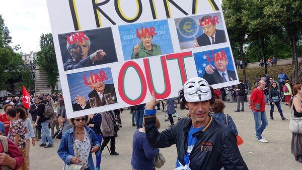 A man holds a sign that reads Troika Out as people take part in a demonstration called by associations, unions and left-wing politicians in support of both migrants and the Greek people on June 20, 2015 in Paris. - Sputnik International