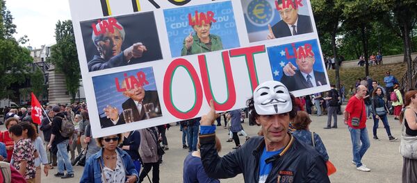 A man holds a sign that reads Troika Out as people take part in a demonstration called by associations, unions and left-wing politicians in support of both migrants and the Greek people on June 20, 2015 in Paris. A man holds a sign that reads Troika Out as people take part in a demonstration called by associations, unions and left-wing politicians in support of both migrants and the Greek people on June 20, 2015 in Paris. - Sputnik International