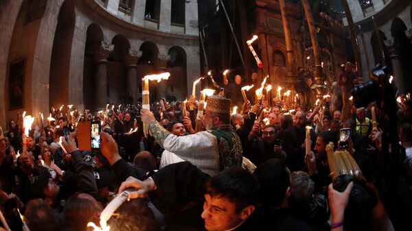 Christian Orthodox worshipers hold up candles lit from the Holy Fire as thousands gather in the Church of the Holy Sepulchre in Jerusalem’s Old City (File) - Sputnik International
