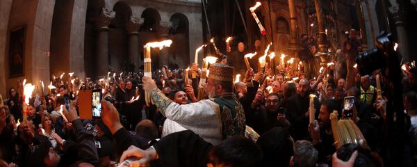 Christian Orthodox worshipers hold up candles lit from the Holy Fire as thousands gather in the Church of the Holy Sepulchre in Jerusalem’s Old City (File) Christian Orthodox worshipers hold up candles lit from the Holy Fire as thousands gather in the Church of the Holy Sepulchre in Jerusalem’s Old City (File) - Sputnik International
